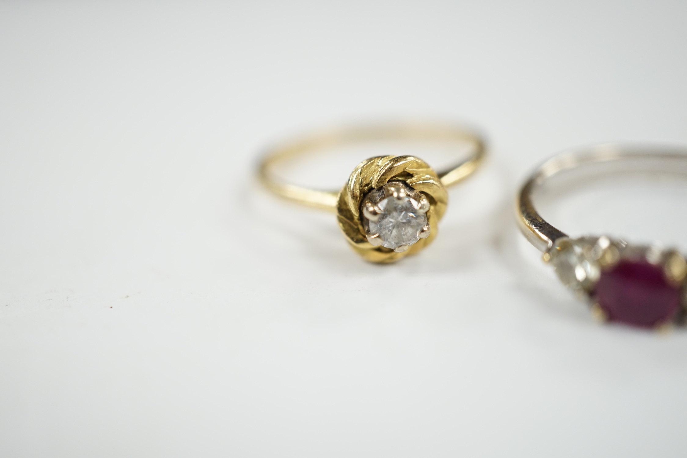 A modern 18ct white gold, ruby and diamond set three stone ring, size N/O and a 1970's 18ct gold and solitaire diamond set ring, size L, gross weight 5.3 grams.